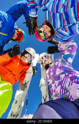 Gruppo di ragazze adolescenti guardare giù con sci e sport invernale vestito in piedi insieme sorridente Foto Stock