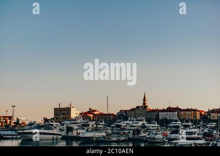 Wharf nella città di Budva, yacht ormeggiati alle mura della città vecchia. Luce solare del tramonto sui tetti. Foto Stock