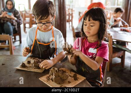 i bambini sono impegnati a giocare artigianato in argilla nella galleria di laboratori di ceramica Foto Stock