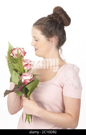 Giovane donna brunetta in un chignon con mazzo di fiori (rose) Foto Stock