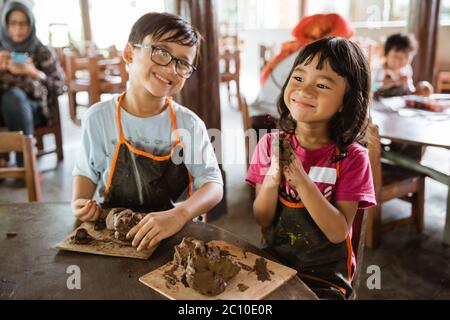 i bambini sono impegnati a giocare artigianato in argilla nella galleria di laboratori di ceramica Foto Stock