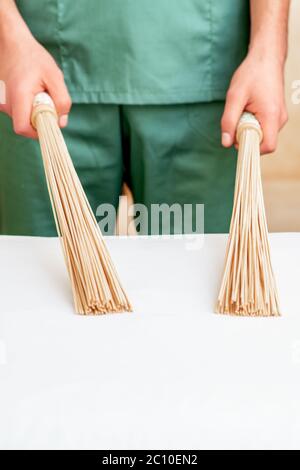 Primo piano di mani di massaggiatore che tiene le ginette di massaggio di bambù sul tavolo. Foto Stock