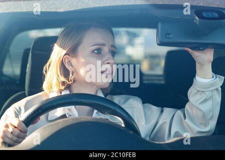 Donna conducente auto per la prima volta, cerca di evitare un incidente d'auto, è molto nervoso e spaventato, preoccupazioni, aggraffatura strettamente alla ruota destra, guardando in Foto Stock