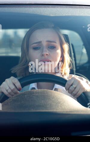 Donna guida la sua auto per la prima volta, cerca di evitare un incidente d'auto, è molto nervoso e spaventato, preoccupazioni, aggraffatura strettamente alla ruota. Inesperienza Foto Stock