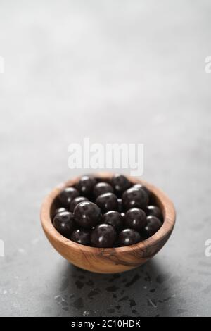 drage al cioccolato con nocciole in ciotola di legno d'oliva Foto Stock