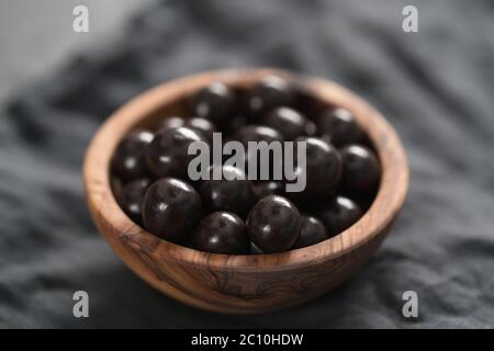 drage al cioccolato con nocciole in ciotola di legno d'oliva Foto Stock