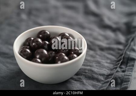 drage al cioccolato con nocciole in ciotola bianca su lino sfondo Foto Stock