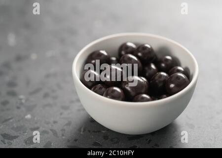 drage al cioccolato con nocciole in ciotola bianca su cemento sfondo Foto Stock