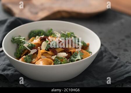 pasta di fettuccine con pomodori secchi, fiocchi di mandorle e foglie di kale Foto Stock