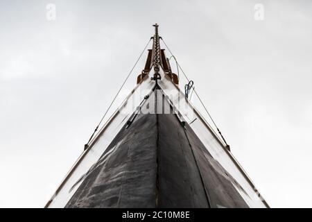 Vista dall'angolo basso della prua di una lussuosa barca a vela in legno contro un cielo nuvoloso. Foto Stock