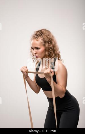 Indossa una tuta nera che si piega leggermente in avanti mentre fai esercizio per il braccio e utilizza una fascia flessibile durante l'allenamento Foto Stock