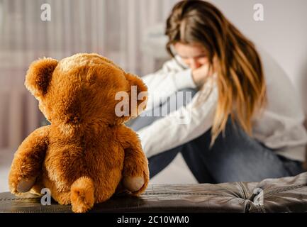 Donna caucasica e orso tedyy pensivi. Messa a fuoco selettiva. Problemi e difficoltà di concetto. Foto Stock