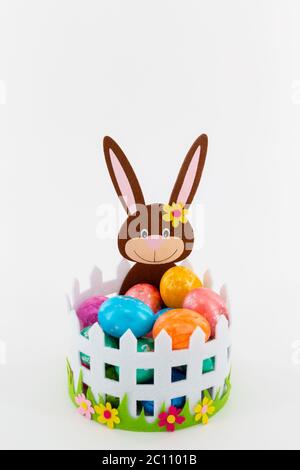 Alcune uova di Pasqua colorate in un cestino con un coniglietto di Pasqua Foto Stock