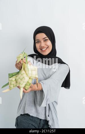 donna con ketupat su sfondo bianco. donna musulmana hijab su eid ramadan con torta di riso piatto tradizionale Foto Stock