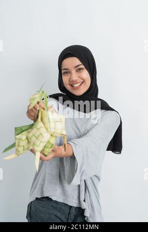 donna con ketupat su sfondo bianco. donna musulmana hijab su eid ramadan con torta di riso piatto tradizionale Foto Stock