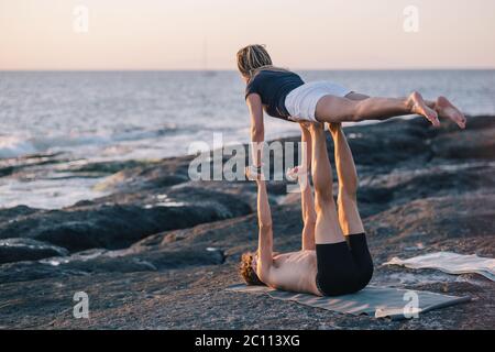 coppia facendo esercizi di yoga all'aperto in spiaggia Foto Stock