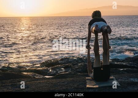 coppia facendo esercizi di yoga all'aperto in spiaggia Foto Stock