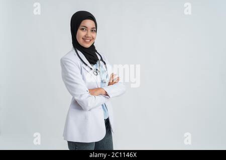 mussulmana bella donna medico in cappotto bianco con stetoscopio, vita in su. Donna operatrice ospedaliera che guarda la macchina fotografica e sorridente Foto Stock