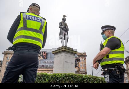 La polizia pattuglia oltre la statua di Robert Peel mentre gli attivisti si riuniscono al cenotafio in George Square, Glasgow, Per proteggerlo da qualsiasi attacco di vandalismo dopo che la Lega di difesa Loyalist ha chiesto ai seguaci di riunirsi per un evento 'Proteggi il Cenotafe' in risposta alle statue che vengono sfidate in Scozia dopo le dimostrazioni della materia di Black Lives. Foto Stock