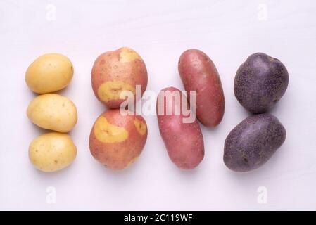 Diversi tipi di patate su tavola rustica in legno bianco Foto Stock