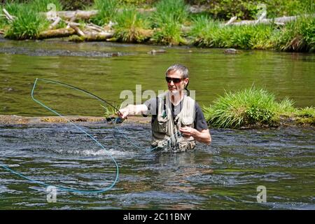 Un pescatore di trote pesca con la trota iridea con un fly rod sul fiume Metolius nelle Cascade Mountains dell'Oregon centrale. Foto Stock