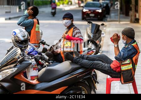 I conducenti di taxi motociclistici con maschere che aspettano i clienti durante la pandemia di Covid, Bangkok, Thailandia Foto Stock