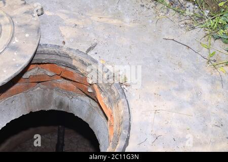 Cesspit di cemento con un portello aperto sul terreno in estate Foto Stock