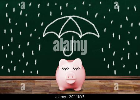 Risparmio per una giornata piovosa con la banca di piggy rosa in classe con lavagna illustrazione di ombrello schermante piggy dalla pioggia. Concetto di secu finanziario Foto Stock