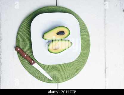 Avocado affettato su piatto bianco e vecchio tavolo di legno bianco Foto Stock