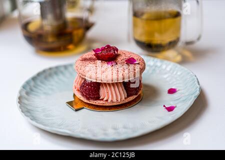 Biscotti rosa di macaron di lamponi su piastra blu. Tempo del tè. Sfondo blu della tabella. Vista dall'alto. Foto Stock