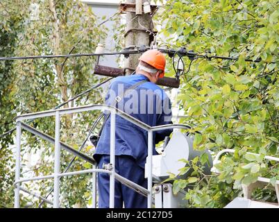 Elettrico riparare i fili sul palo con l aiuto della macchina di sollevamento. Foto Stock