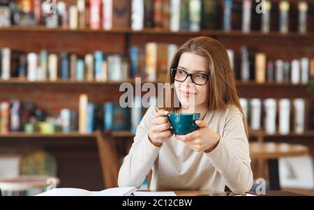 Giovane ragazza pusiva che ha pausa caffè al caffè da solo Foto Stock