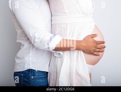 coppia incinta innamorato del ventre del bambino. Mani sullo stomaco bambino bump. Marito mano incinta pancia Foto Stock