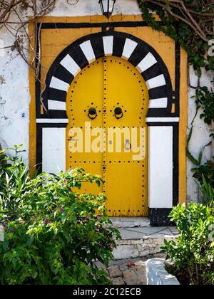 Porta decorata in modo elaborato di una casa tradizionale a Sidi bou Said, Tunisia, in stile moresco con arco e decorazioni dipinte Foto Stock