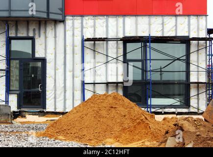 cumulo di sabbia e impalcature in cantiere vicino al sotto edificio appartamento. Foto Stock