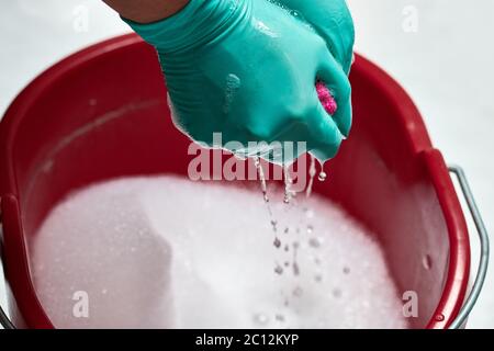 Primo piano delle mani con guanti stropicchianti su un panno in microfibra, isolato su sfondo bianco Foto Stock