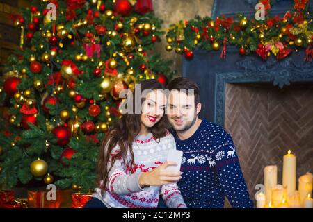 Giovane coppia vicino camino per festeggiare Natale Foto Stock