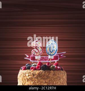 Lamponi blackberry torta di compleanno con candele numero 30 su uno sfondo di legno e copyspace per il testo Foto Stock