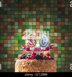 Lamponi blackberry torta di compleanno con candele numero 30 su sfondo piastrelle e copyspace per il testo Foto Stock