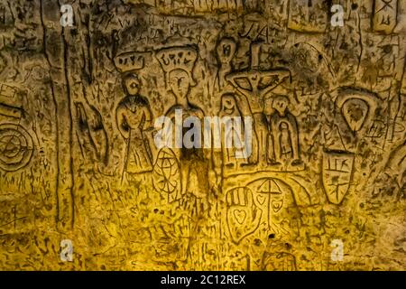 Il Royston Cave è decorato con una varietà di sculture a bassorilievo. Sono principalmente motivi cristiani in stile medievale. Ecco una scena di crocifissione. Le due figure sotto St Katherine potrebbero essere re Richard i, conosciuto come re Lionheart e sua moglie Berengaria la cui corona è mostrata galleggiare sopra la sua testa come non era mai realmente regina incoronata. Sotto la crocifissione una palma con un cuore inciso. Royston Cave in Katherine's Yard, Melbourn Street, Royston, Inghilterra Foto Stock