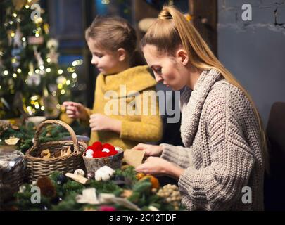 Donna con ragazza che decora la corona conifera Foto Stock