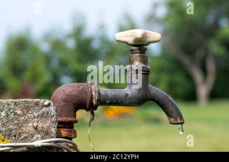 Un vecchio arrugginito rubinetto di acqua in giardino. Foto Stock