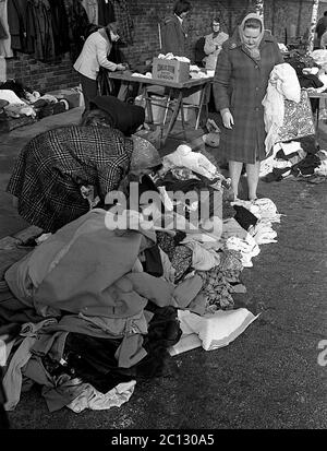 AJAXNETPHOTO. 27 FEBBRAIO 1975. PORTSMOUTH, INGHILTERRA. - MERCATO DELLE PULCI - IN STRADA UNICORN; BUYER RUMMAGE ATTRAVERSO I BENI USATI E VESTITI SPARSI SUL PAVEMENT.PHOTO:JONATHAN EASTLAND/AJAX REF:7513 18 118 Foto Stock