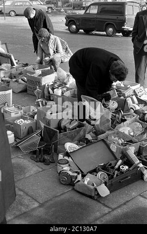 AJAXNETPHOTO. 27 FEBBRAIO 1975. PORTSMOUTH, INGHILTERRA. - MERCATO DELLE PULCI - IN STRADA UNICORN; BUYER RUMMAGE ATTRAVERSO I BENI USATI E VESTITI SPARSI SUL PAVEMENT.PHOTO:JONATHAN EASTLAND/AJAX REF:7513 19 134 Foto Stock