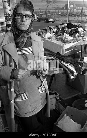 AJAXNETPHOTO. 27 FEBBRAIO 1975. PORTSMOUTH, INGHILTERRA. - MERCATO DELLE PULCI - IN STRADA UNICORN; COMMERCIANTE DI STRADA CON TAVOLO DI TRESPOLO IMPILATO ALTO CON VECCHIO ABBIGLIAMENTO.PHOTO:JONATHAN EASTLAND/AJAX REF:7513 23A 114 Foto Stock