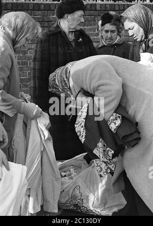 AJAXNETPHOTO. 27 FEBBRAIO 1975. PORTSMOUTH, INGHILTERRA. - MERCATO DELLE PULCI - IN STRADA UNICORN; BUYER RUMMAGE ATTRAVERSO I BENI USATI E VESTITI SPARSI SUL PAVEMENT.PHOTO:JONATHAN EASTLAND/AJAX REF:7513 27 135 Foto Stock