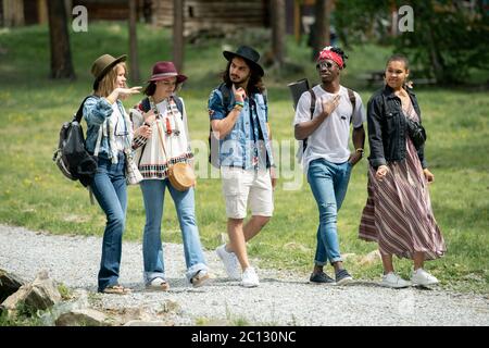Gruppo di giovani amici multietnici camminano insieme e parlano mentre si godono i fine settimana al campeggio festival Foto Stock