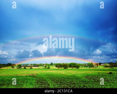 doppio arcobaleno dopo una tempesta di tughi su un campo verde. Foto Stock