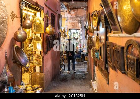 Marrakech, Marocco: Un vicolo stretto all'interno della medina con negozi o souk che vendono illuminazione e oggetti di arredamento per la casa illuminati Foto Stock