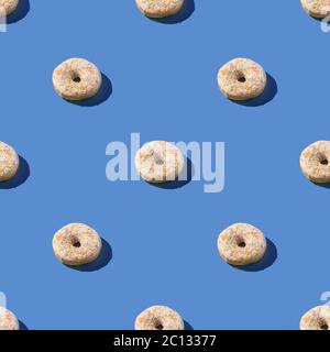 Ciambelle bianche alla vaniglia con spruzzette, dolce dessert satinato senza cuciture motivo su sfondo blu Foto Stock